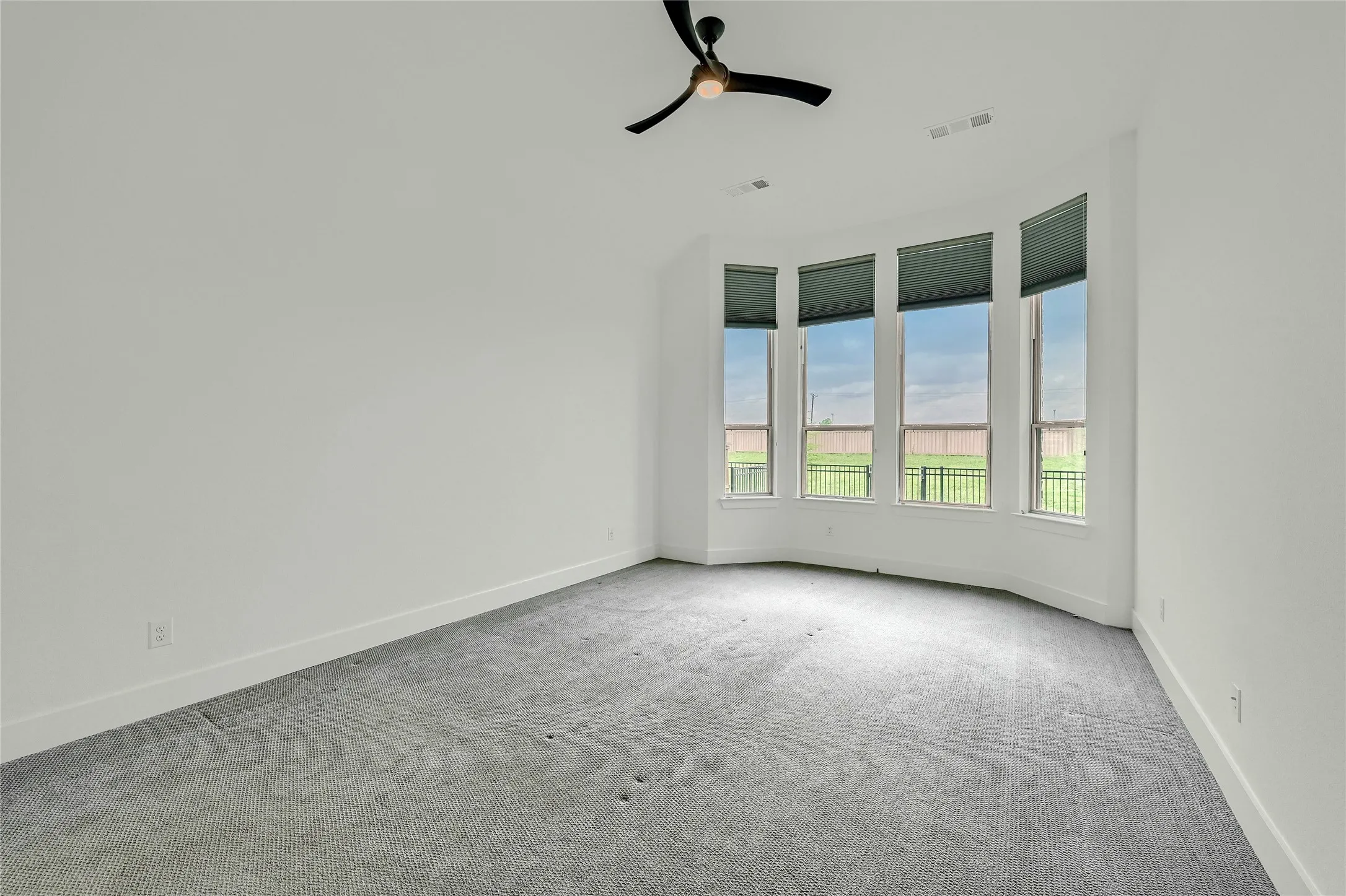 Unfurnished room with baseboards, ceiling fan, carpet, and visible vents