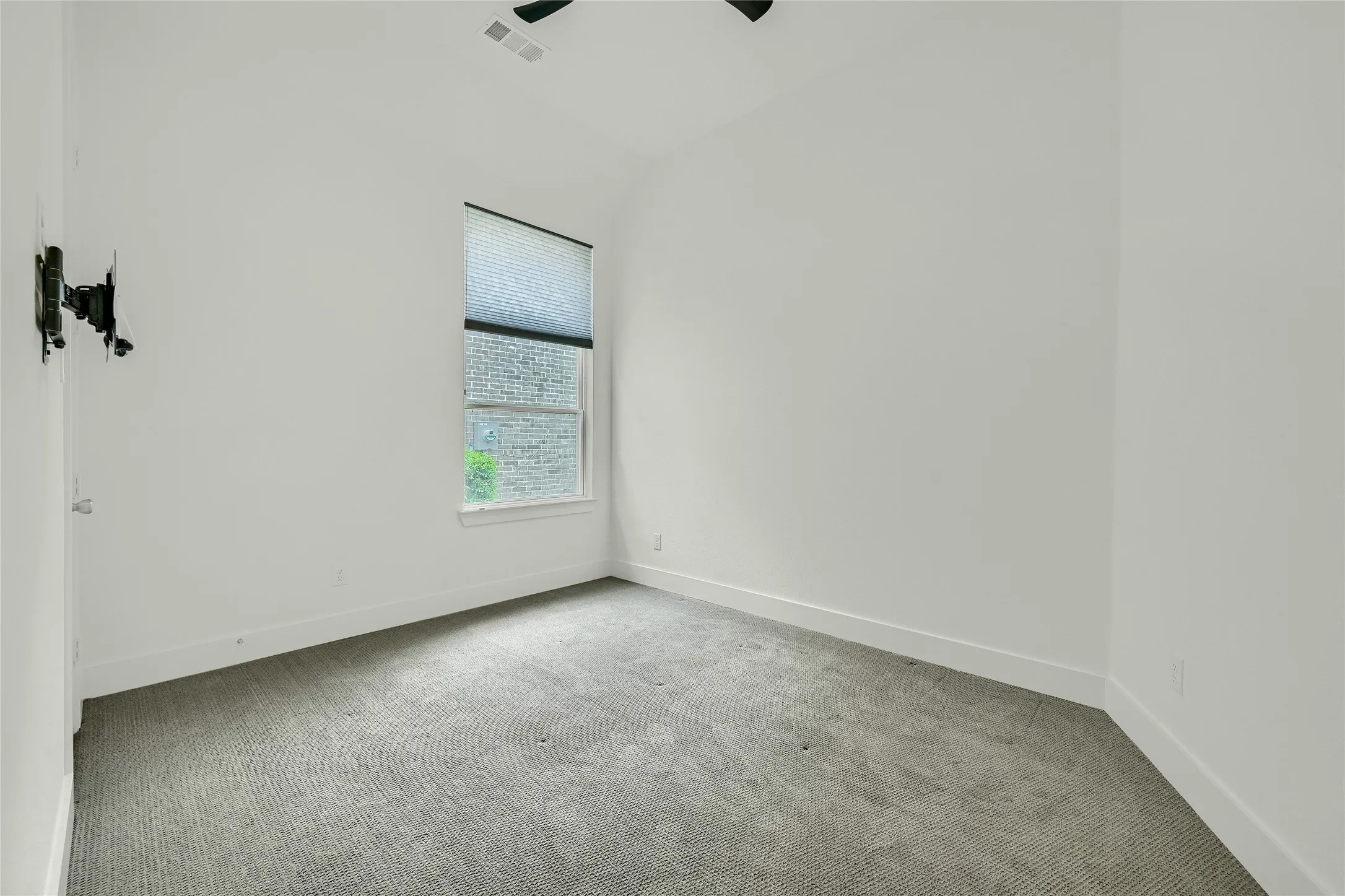 Carpeted spare room featuring visible vents, baseboards, ceiling fan, and vaulted ceiling