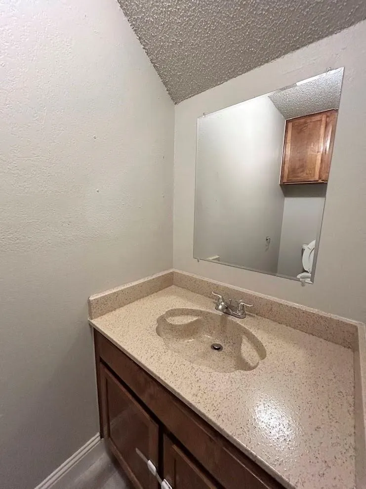 Bathroom vanity featuring a speckled countertop with an integrated sink and chrome faucet
