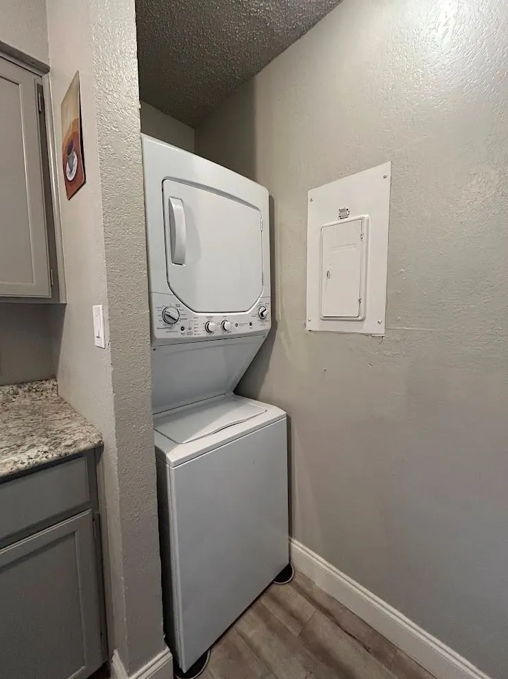 Compact laundry area featuring a stacked washer and dryer unit