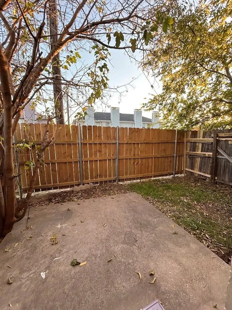 Private backyard featuring a concrete patio, wood privacy fencing, and mature trees