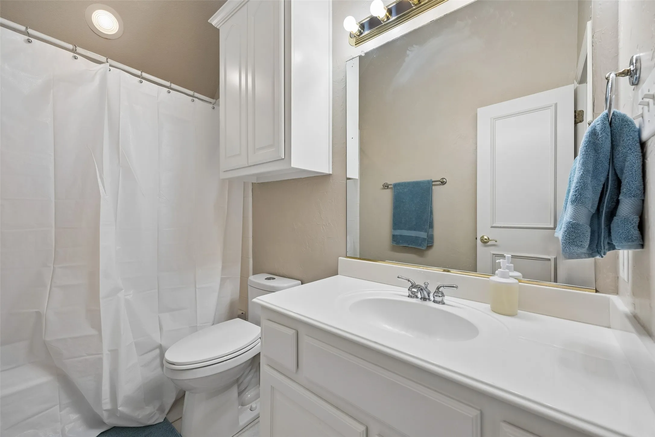 Bathroom featuring a white vanity with integrated sink, chrome faucet, and overhead lighting