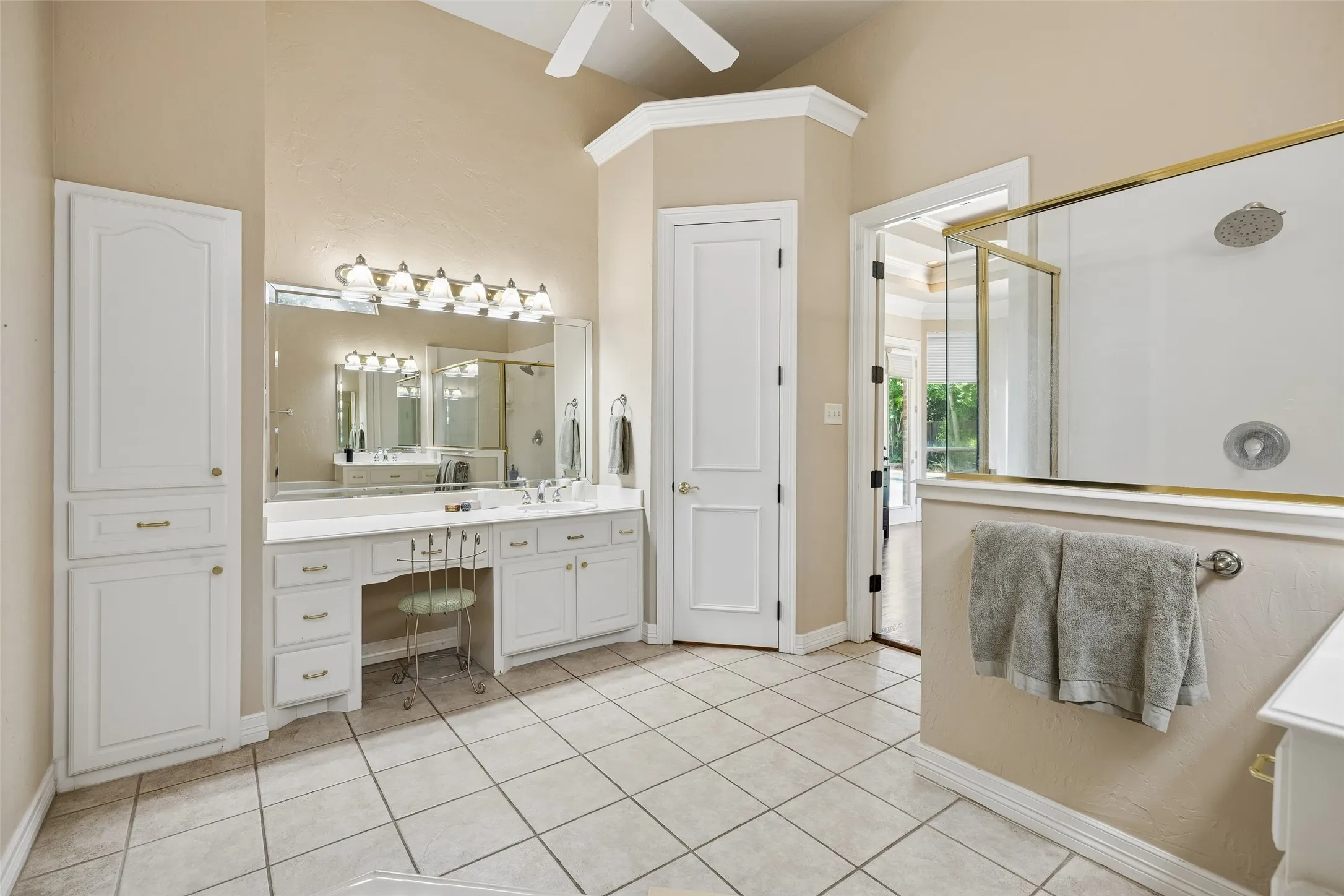 Spacious bathroom featuring a dual vanity, built-in storage cabinetry, tiled flooring, and a glass-enclosed shower