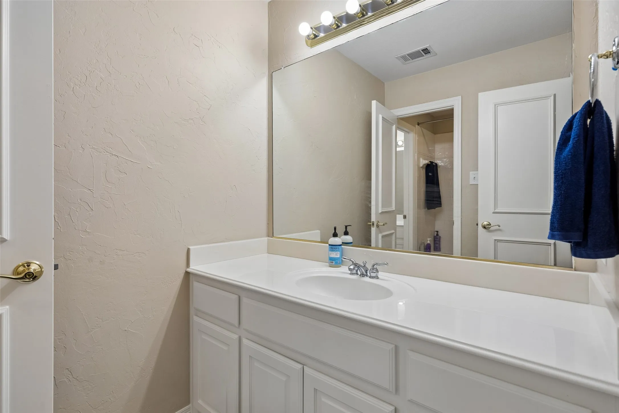 Bathroom vanity featuring a white countertop with an integrated sink, polished chrome faucet, and white cabinetry