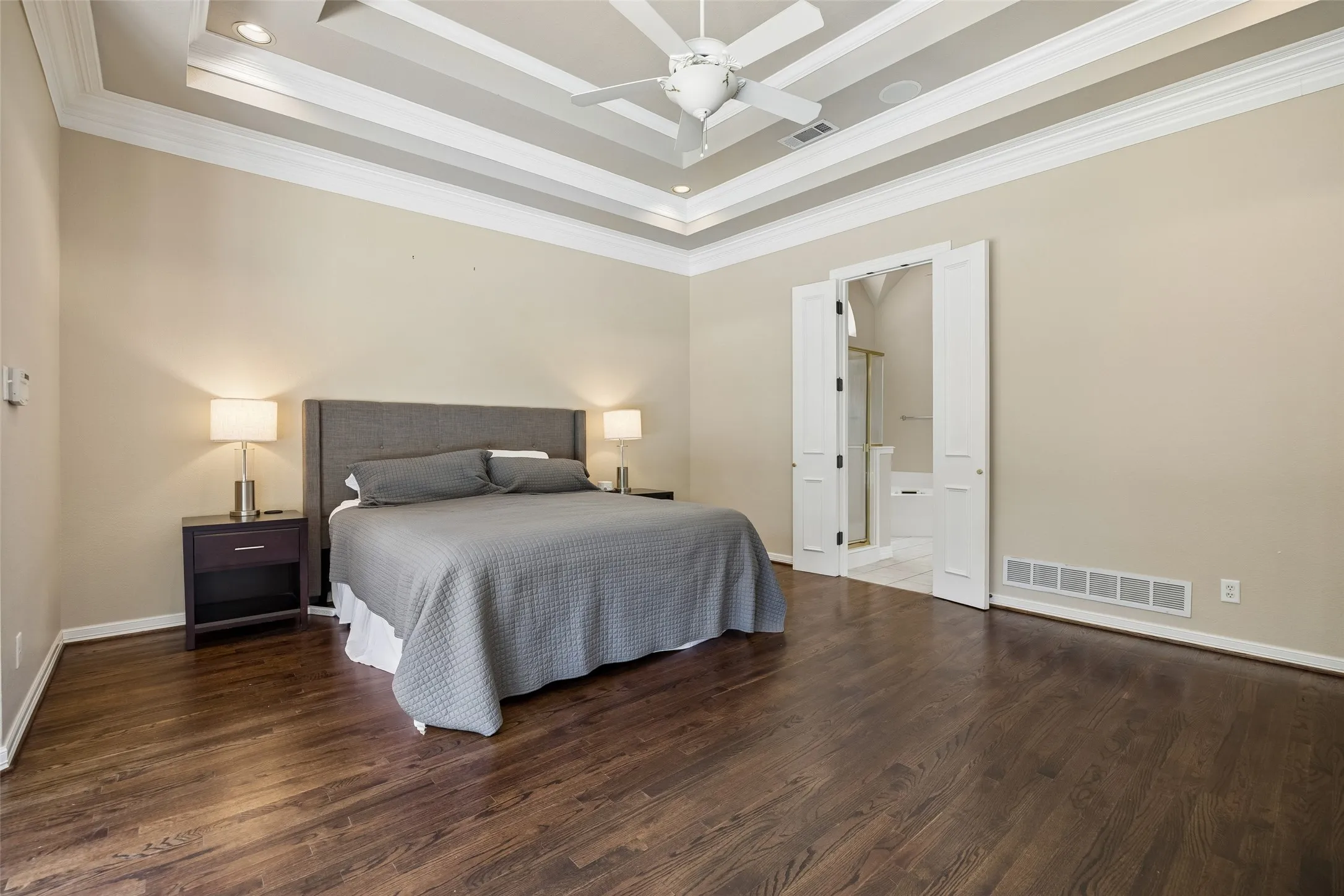 Spacious room with wood-finish flooring, a tray ceiling with recessed lighting, and a ceiling fan