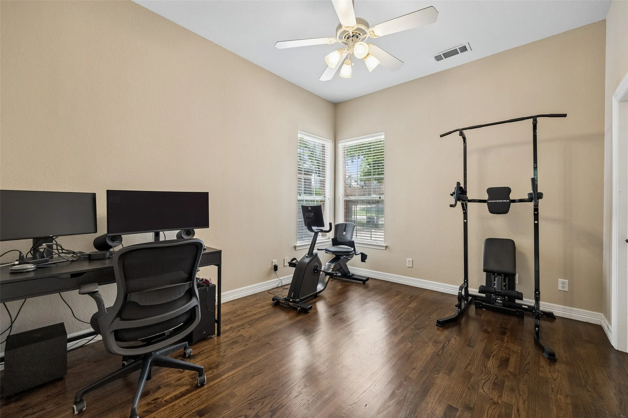 Spacious room featuring rich wood-finish flooring, neutral wall tones, and white trim