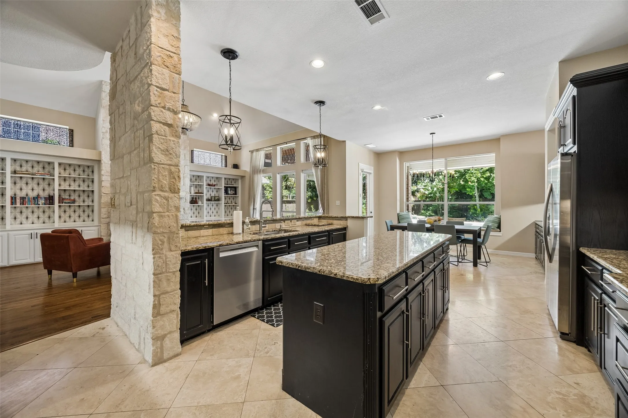 Spacious kitchen featuring an expansive center island with granite countertops, dark wood cabinetry, stainless steel appliances, and tile flooring