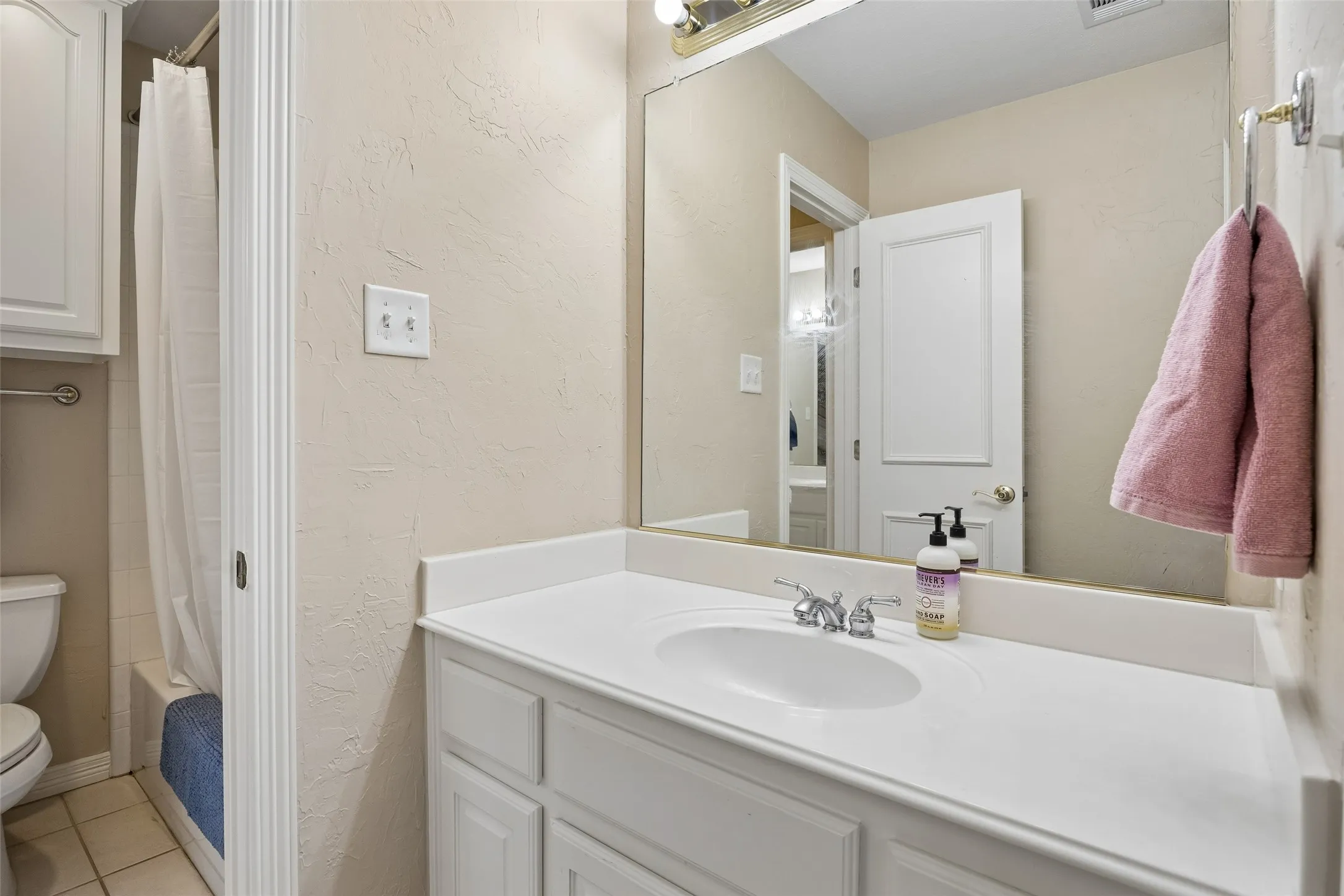 Bathroom featuring a white vanity with an integrated sink, polished chrome faucet, and a large wall-mounted mirror