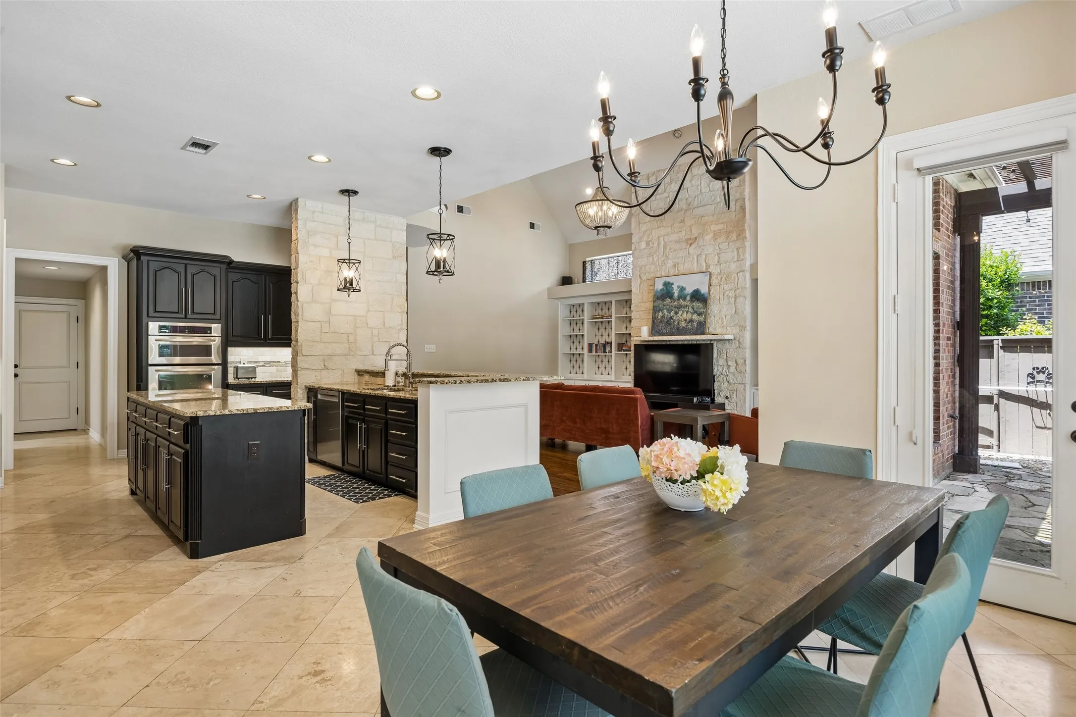 Open-concept kitchen and dining area featuring stone tile flooring