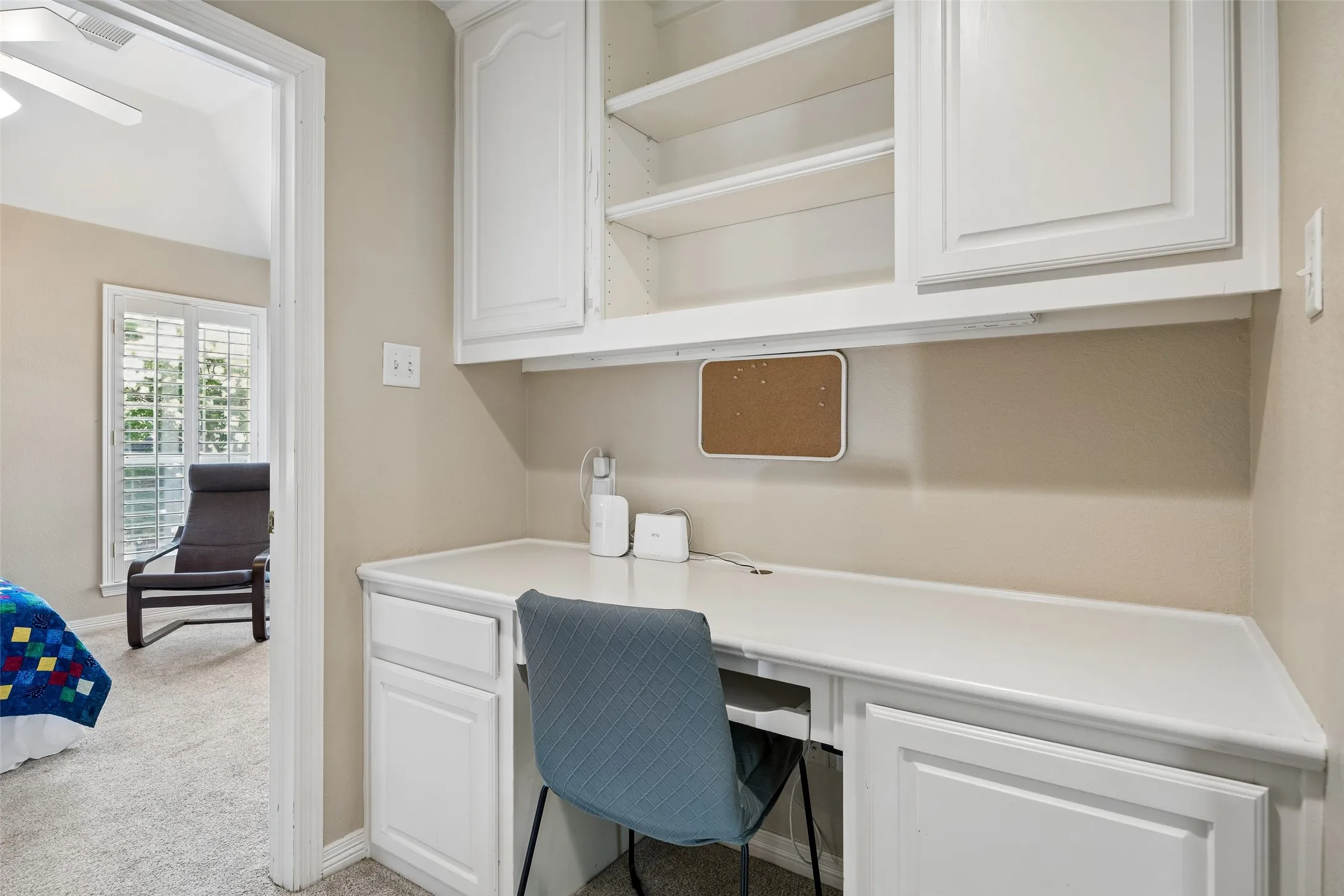 Built-in desk area featuring white cabinetry, integrated shelving, and a light-colored countertop