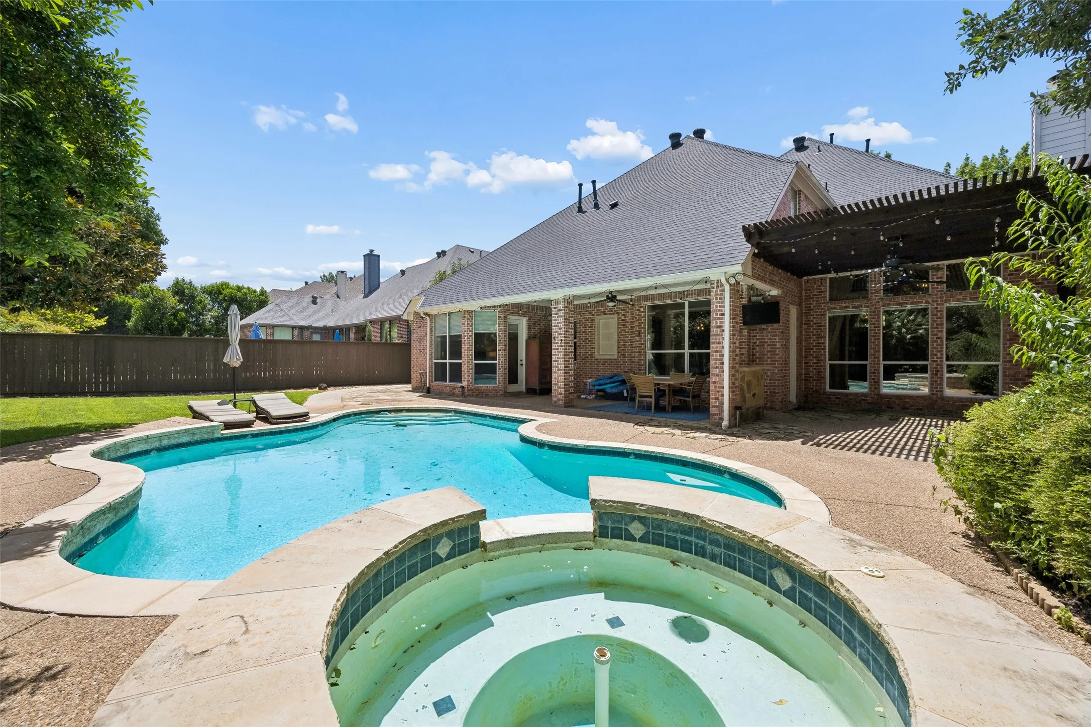 Freeform swimming pool with integrated spa and surrounding aggregate concrete decking