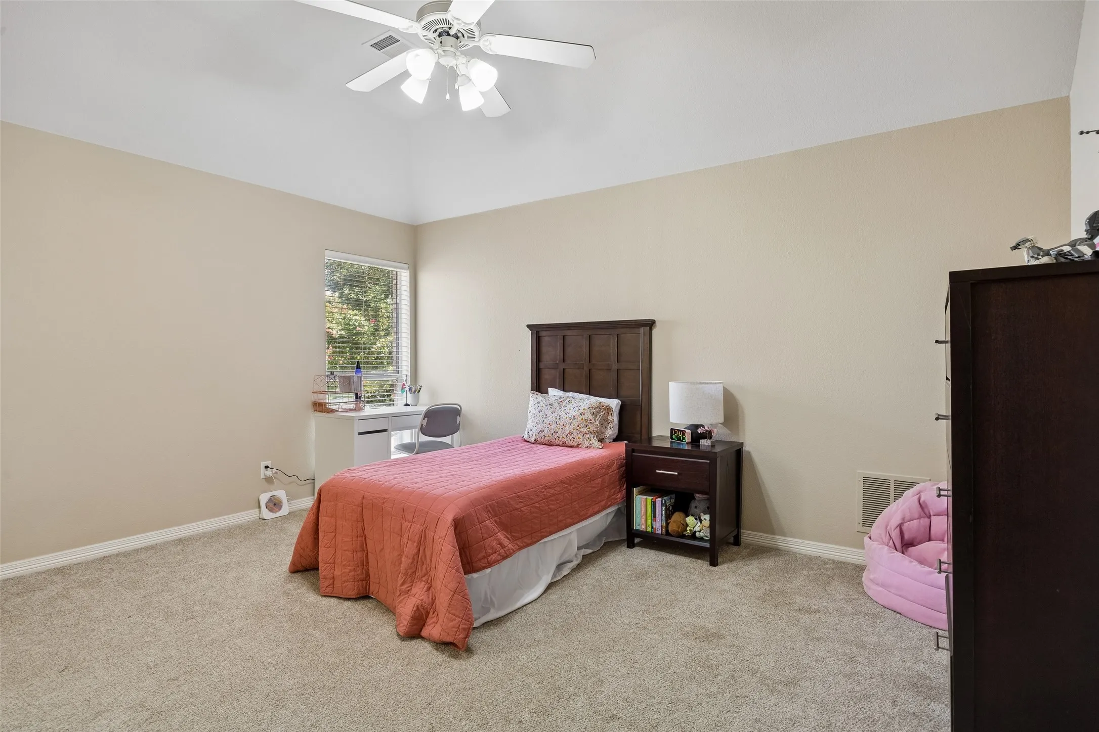 Carpeted bedroom with a vaulted ceiling, ceiling fan with light fixture, and a window with blinds