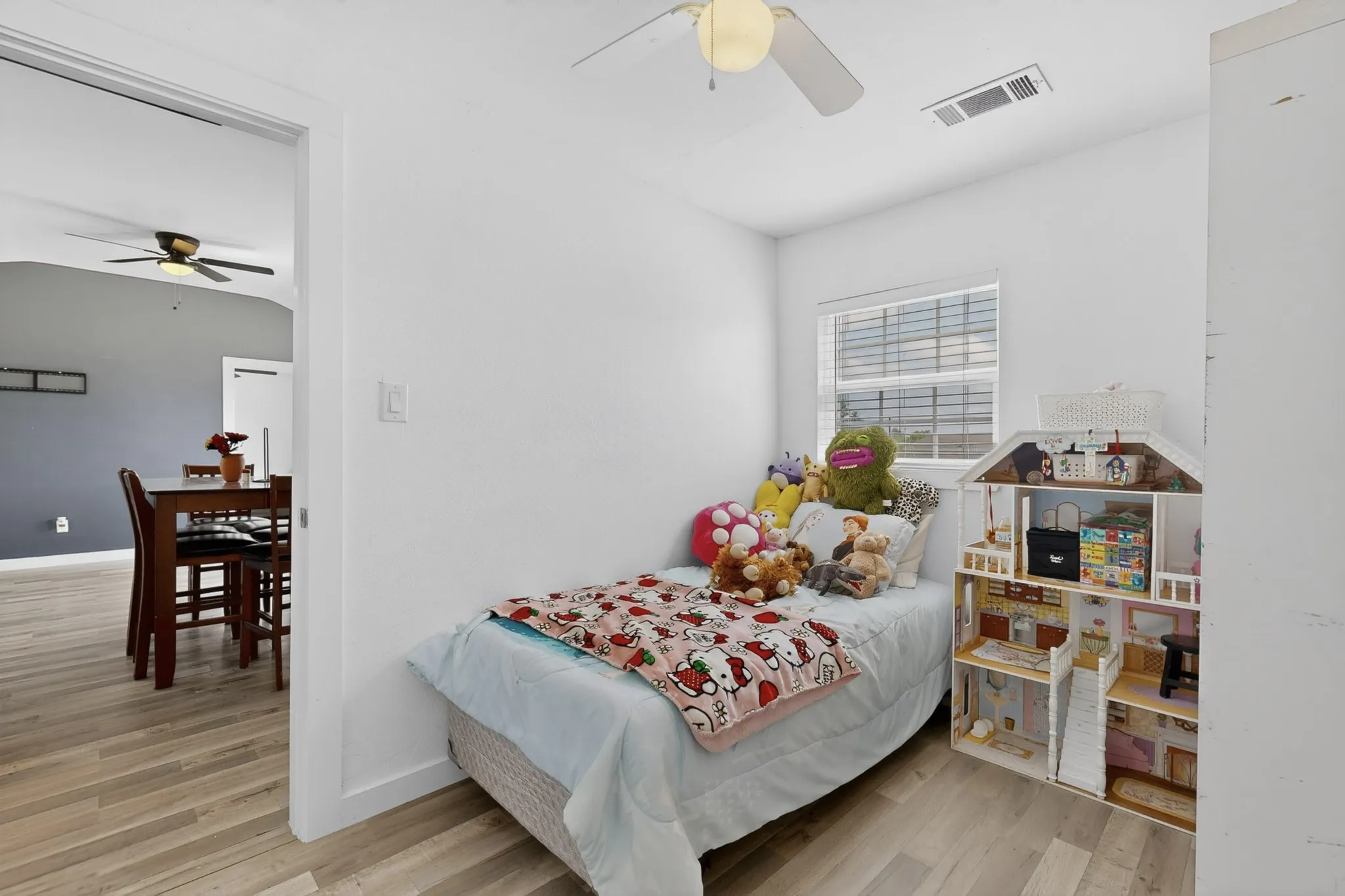Bright room featuring light wood-finish flooring and a ceiling fan with integrated lighting