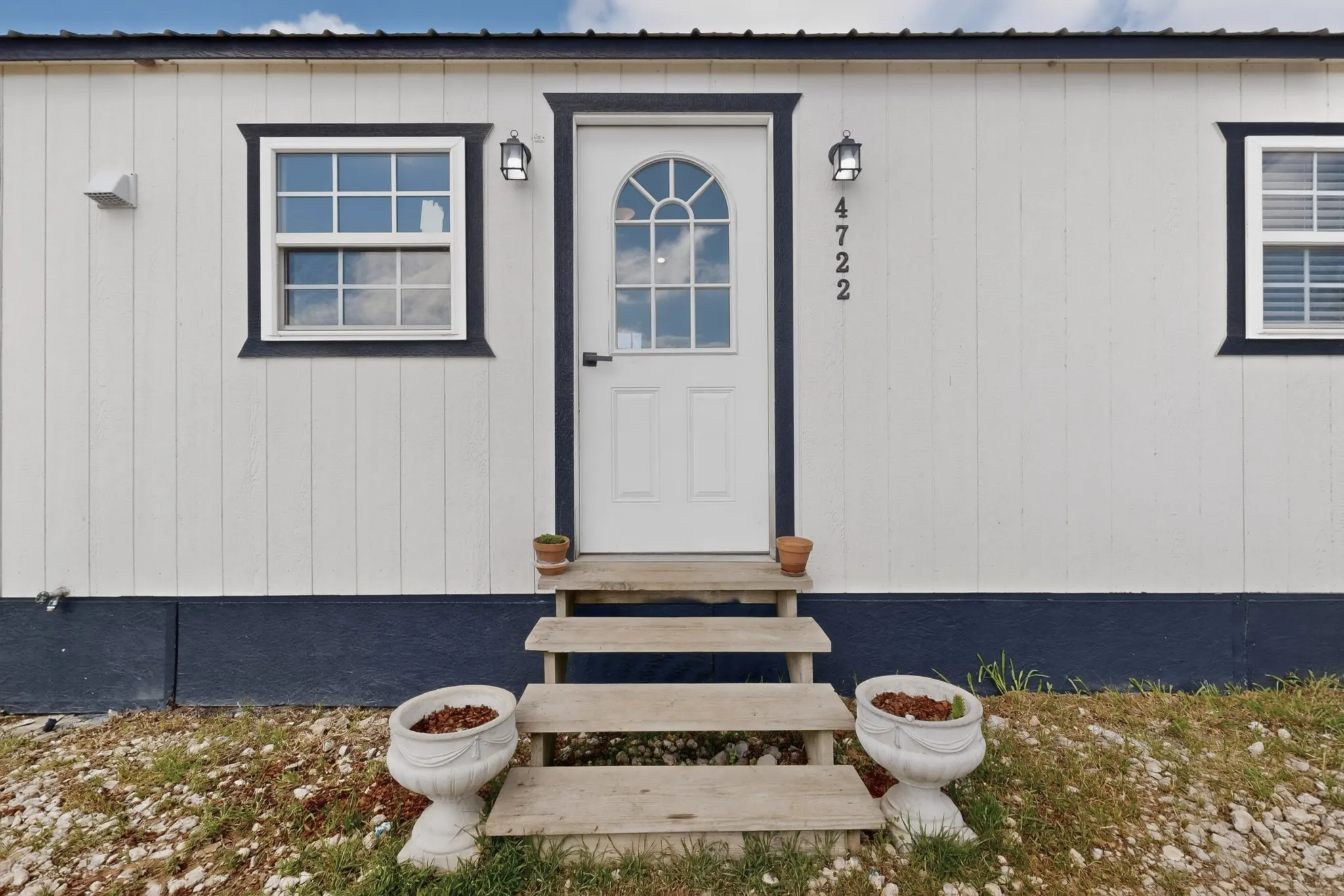 White vertical siding exterior with dark trim and a dark metal roof