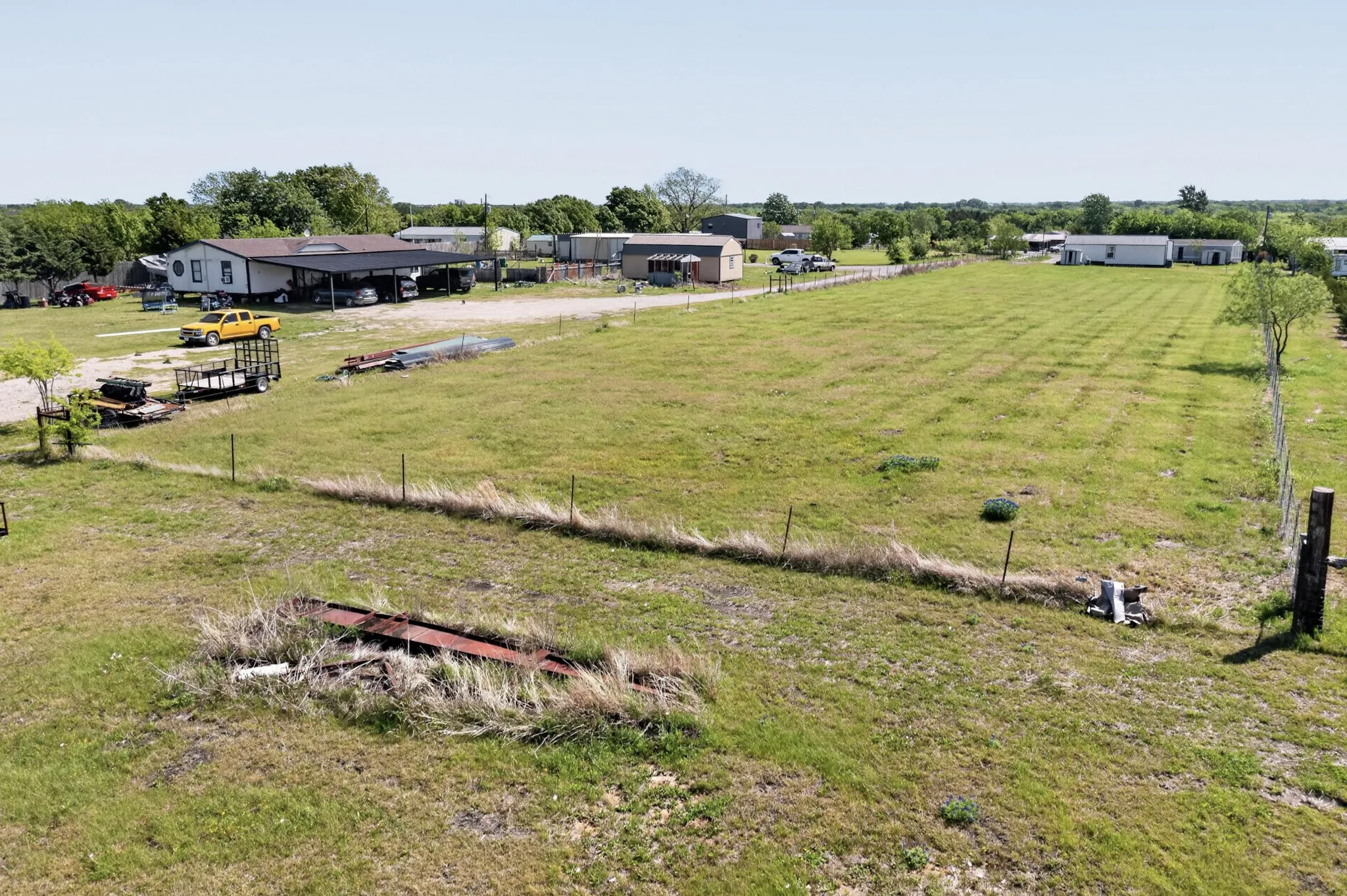 Expansive open land featuring a grassy field and partial wire​​‌​​​​‌​​‌‌​‌‌​​​‌‌​‌​‌​‌​​​‌​​ fencing