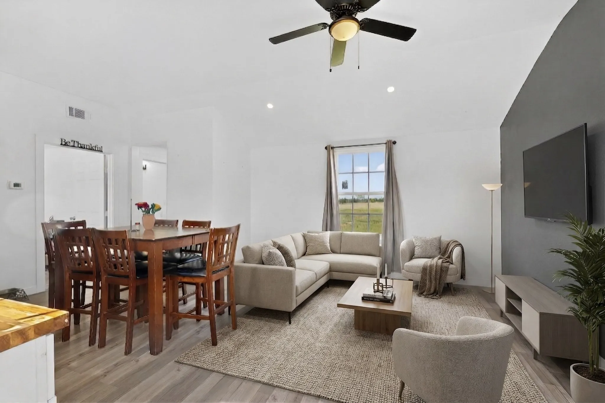 Spacious living area featuring wood-finish flooring, a ceiling fan, recessed lighting, and a large window