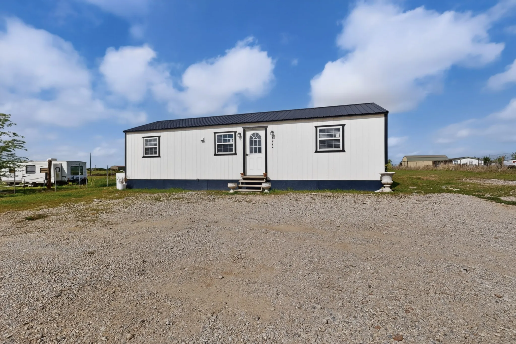 White siding exterior featuring black trim windows and a black metal roof