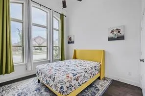Vaulted ceiling with a ceiling fan, three large windows with white trim, dark wood-finish flooring, and white baseboards