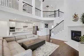 Open-concept living space featuring high ceilings, dark wood-finish flooring, and a fireplace with white mantel