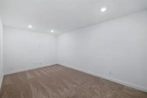 Spacious room featuring neutral carpeting, white walls, recessed ceiling lighting, and white baseboards