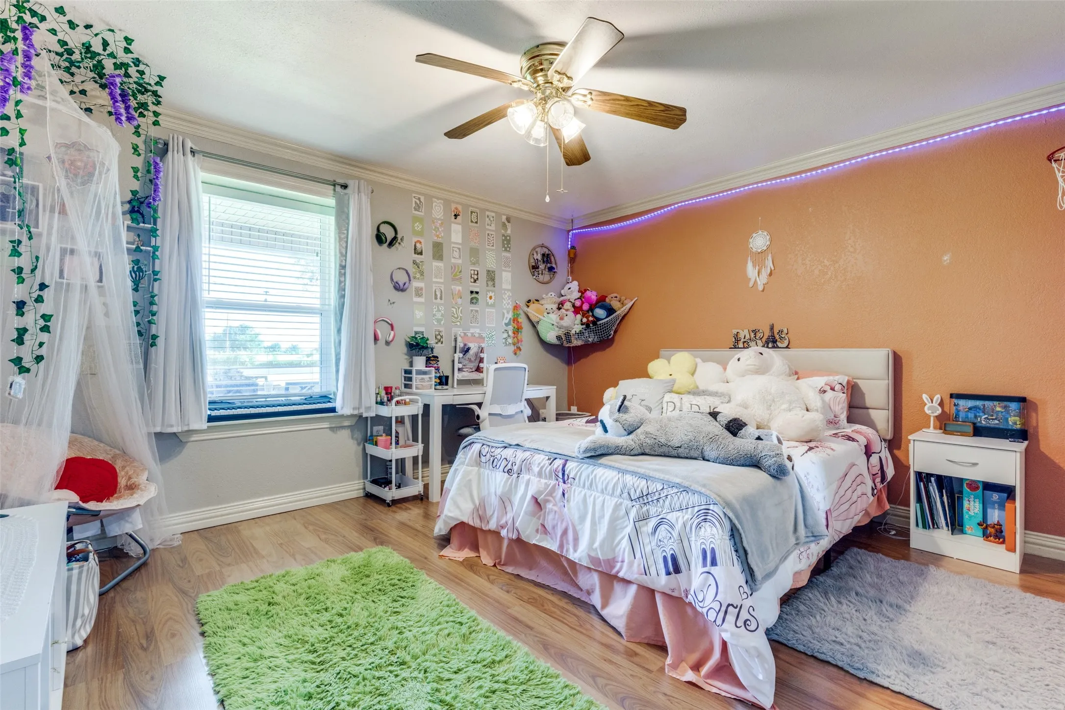 Bedroom featuring wood finished floors, ornamental molding, and a ceiling fan