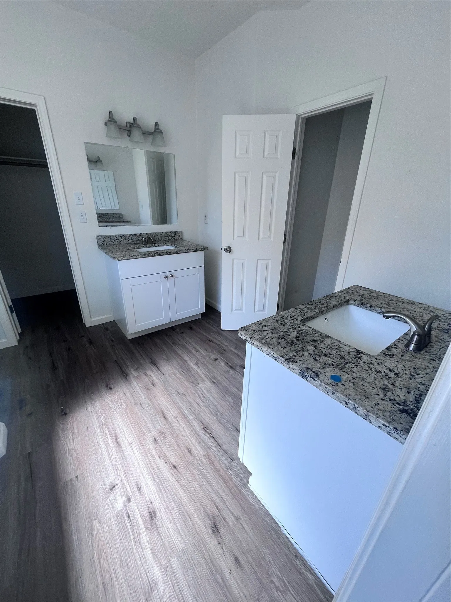 Bathroom featuring two white vanities with granite-finish countertops and undermount sinks