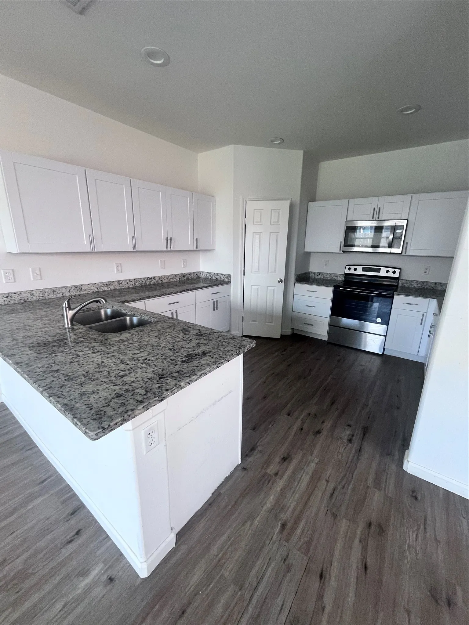 Kitchen featuring a central island with dual basin sink and stone-finish countertop
