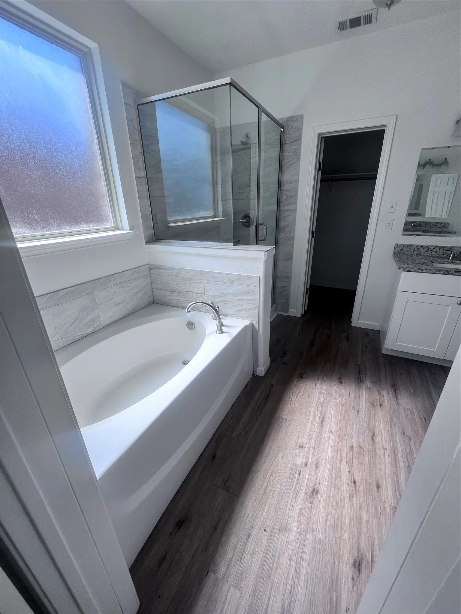 Soaking tub with a tiled surround, adjacent to a glass-enclosed shower