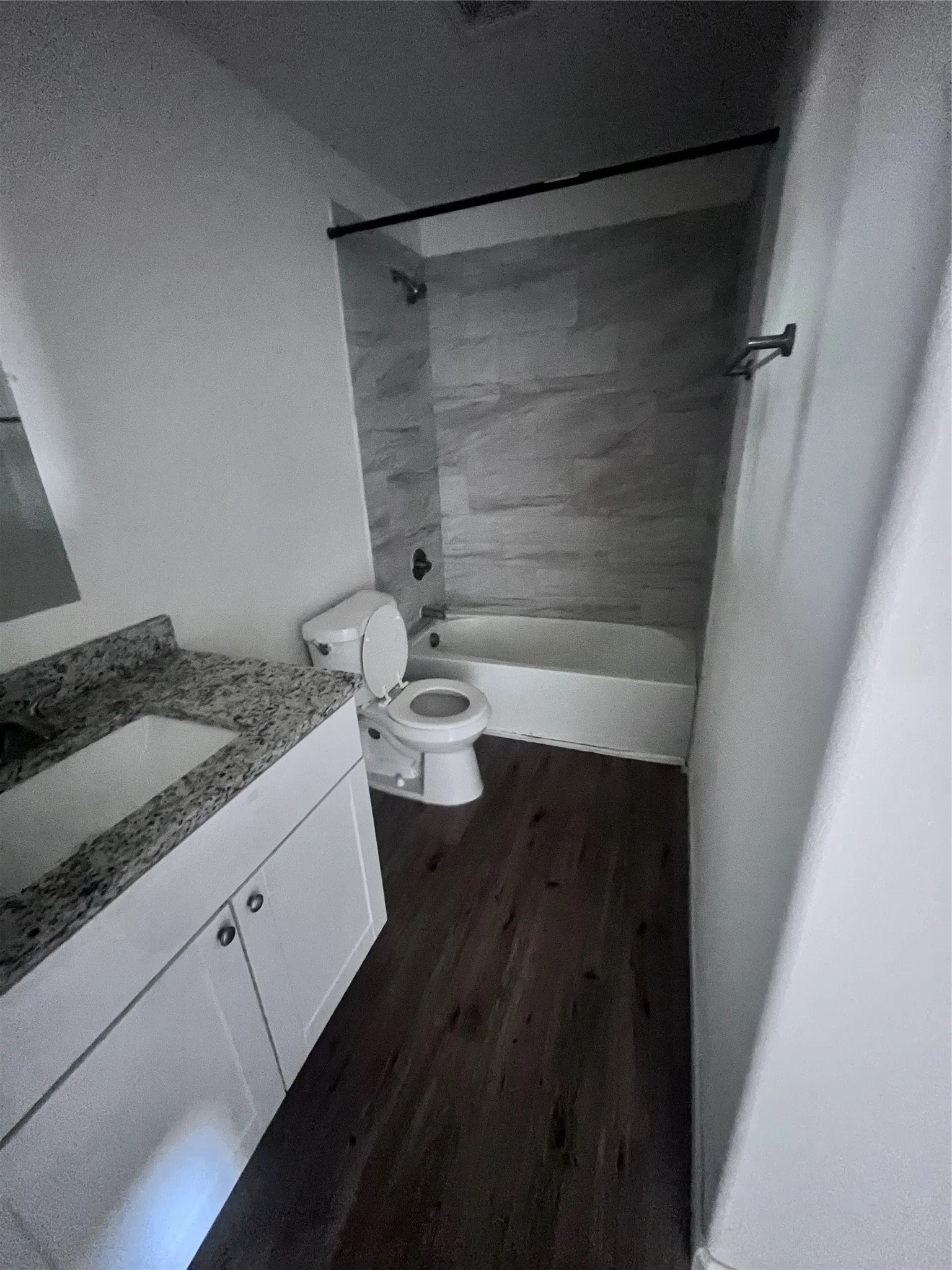 Bathroom featuring a white vanity with a granite countertop, undermount sink, and dark wood-finish flooring