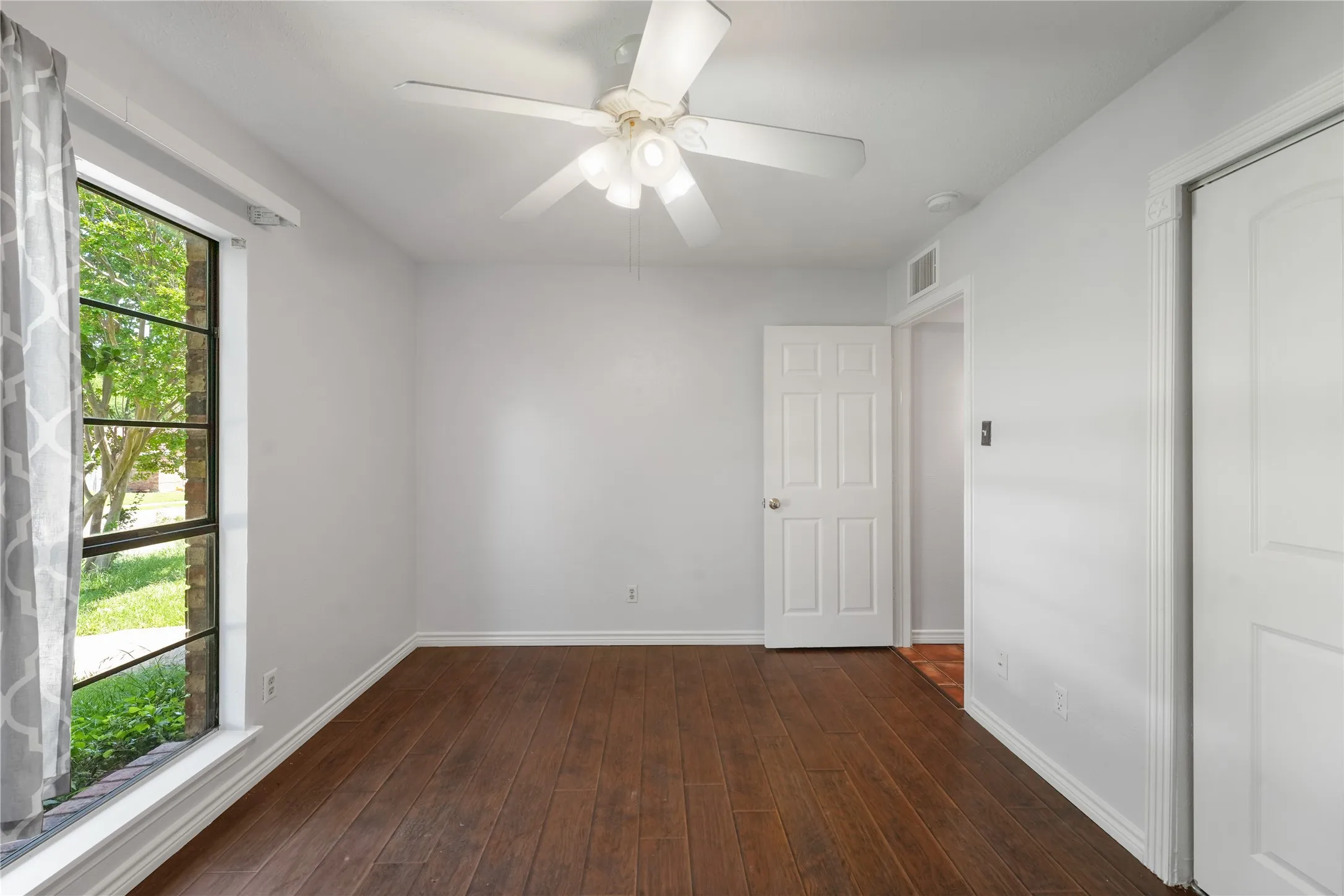 Empty room featuring ceiling fan and dark hardwood / wood-style flooring