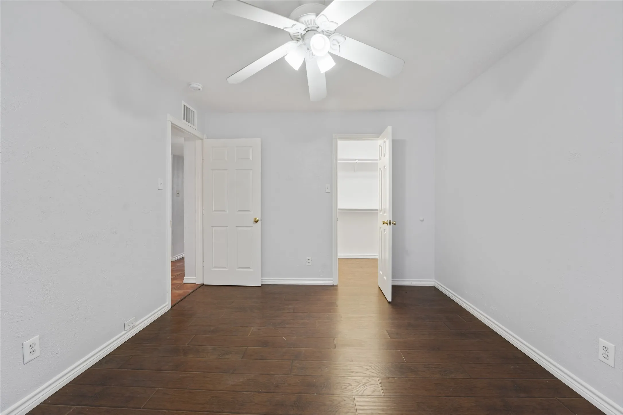 Unfurnished bedroom with a closet, ceiling fan, dark hardwood / wood-style flooring, and a spacious closet