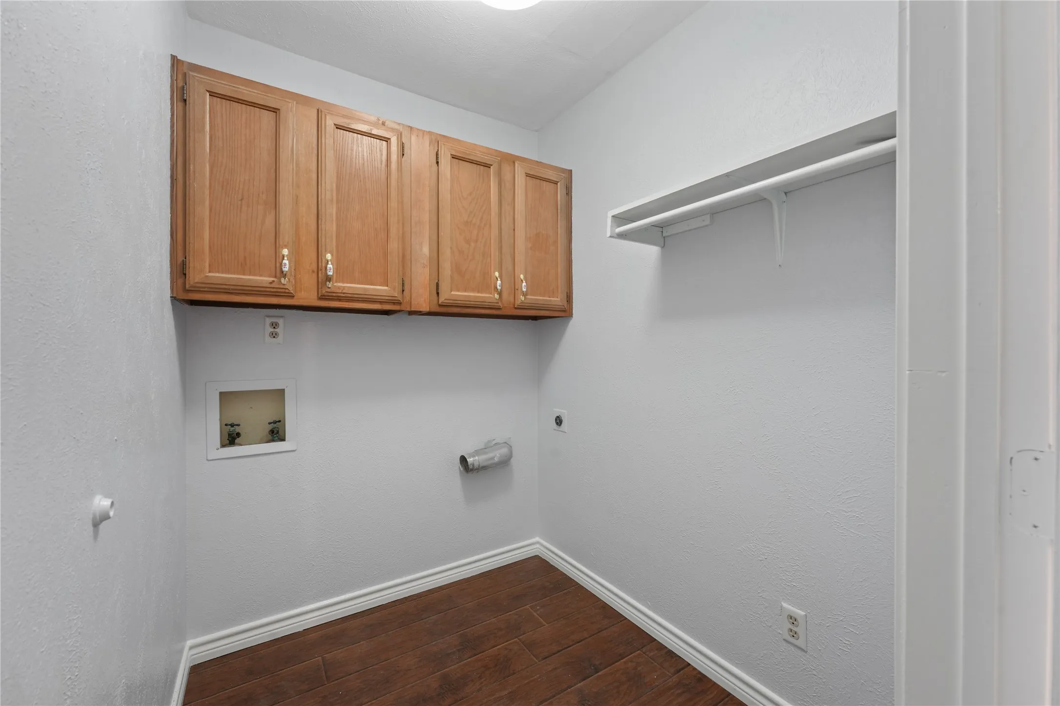 Laundry area with washer hookup, dark wood-type flooring, electric dryer hookup, and cabinets