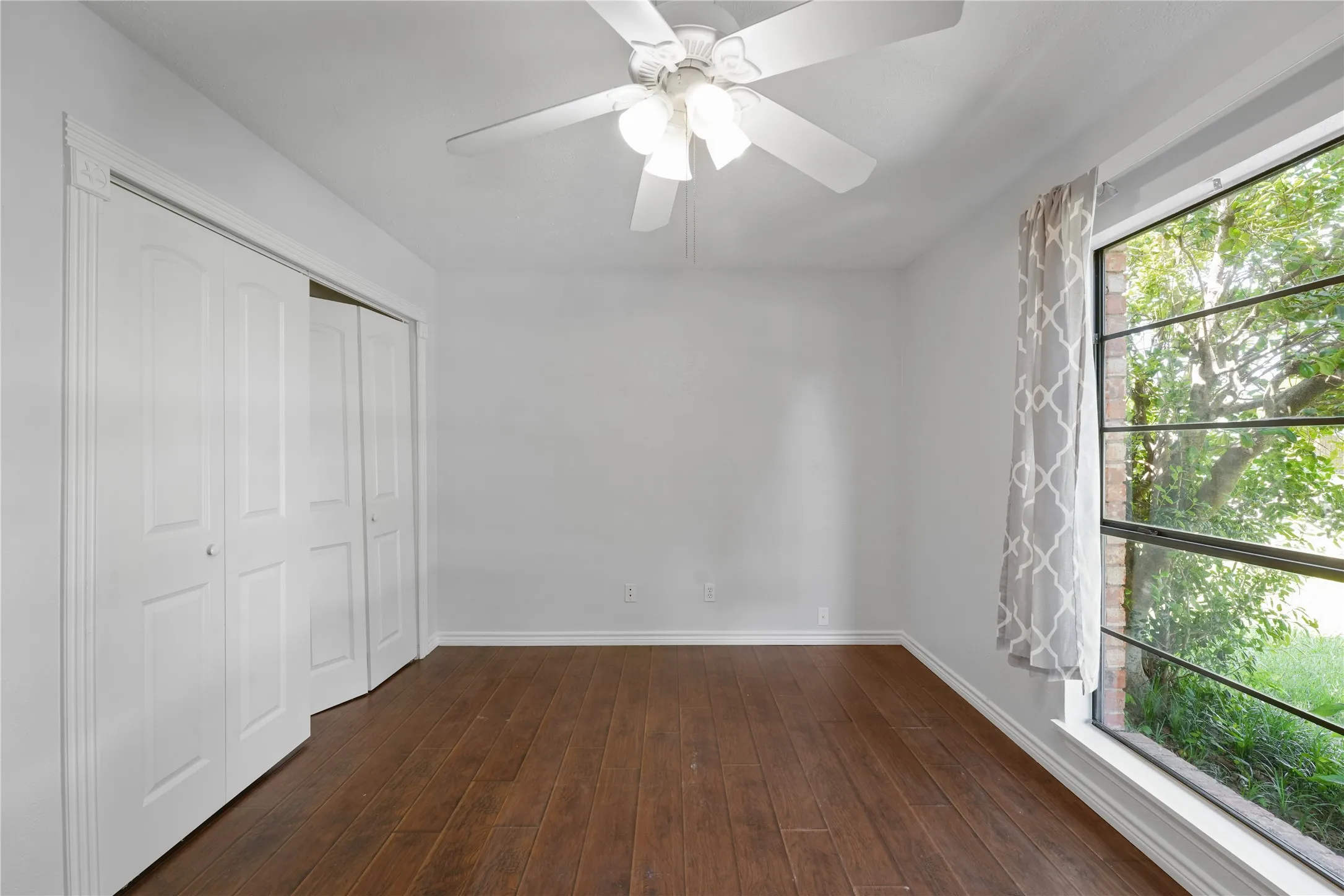 Unfurnished bedroom featuring a closet, dark wood-type flooring, and ceiling fan