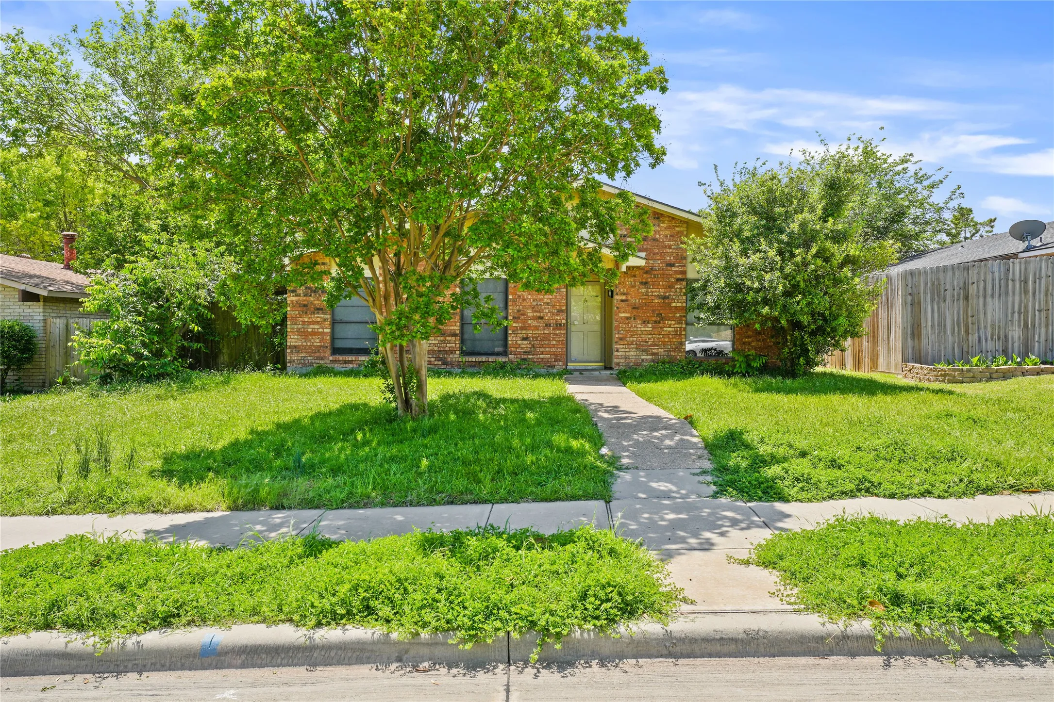 View of property hidden behind natural elements featuring a front yard