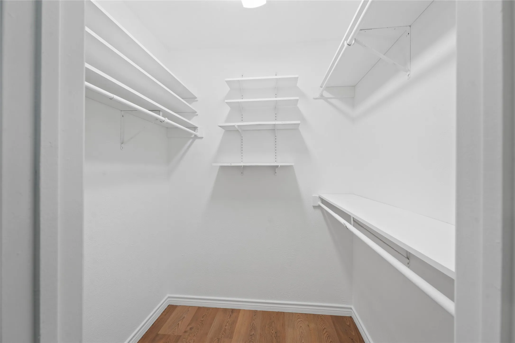 Walk in closet with wood-type flooring