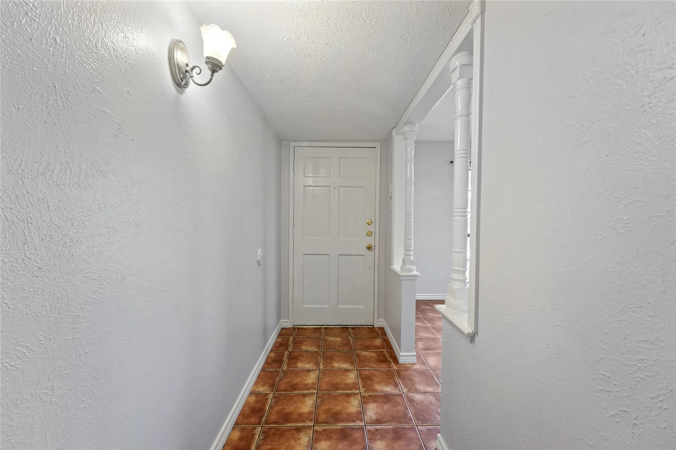Hallway with a textured ceiling and dark tile flooring