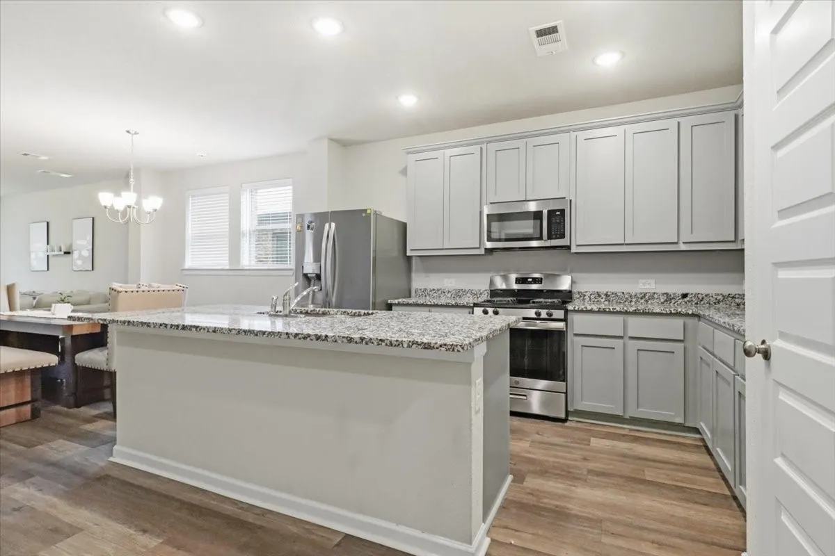 Kitchen featuring light-toned cabinetry, granite countertops, stainless steel appliances, and wood-finish flooring
