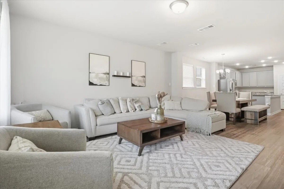 Open-concept living area featuring wood-finish flooring, recessed lighting, and a neutral color palette