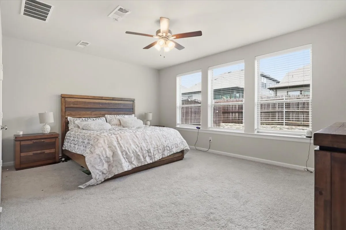 Carpeted room featuring multiple windows with blinds, a ceiling fan, and light-toned walls