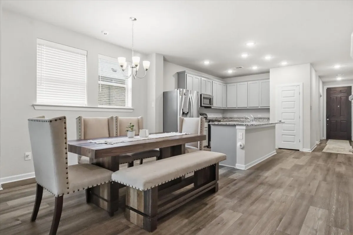 Open-concept living area with wood-finish flooring, recessed lighting, and a modern chandelier