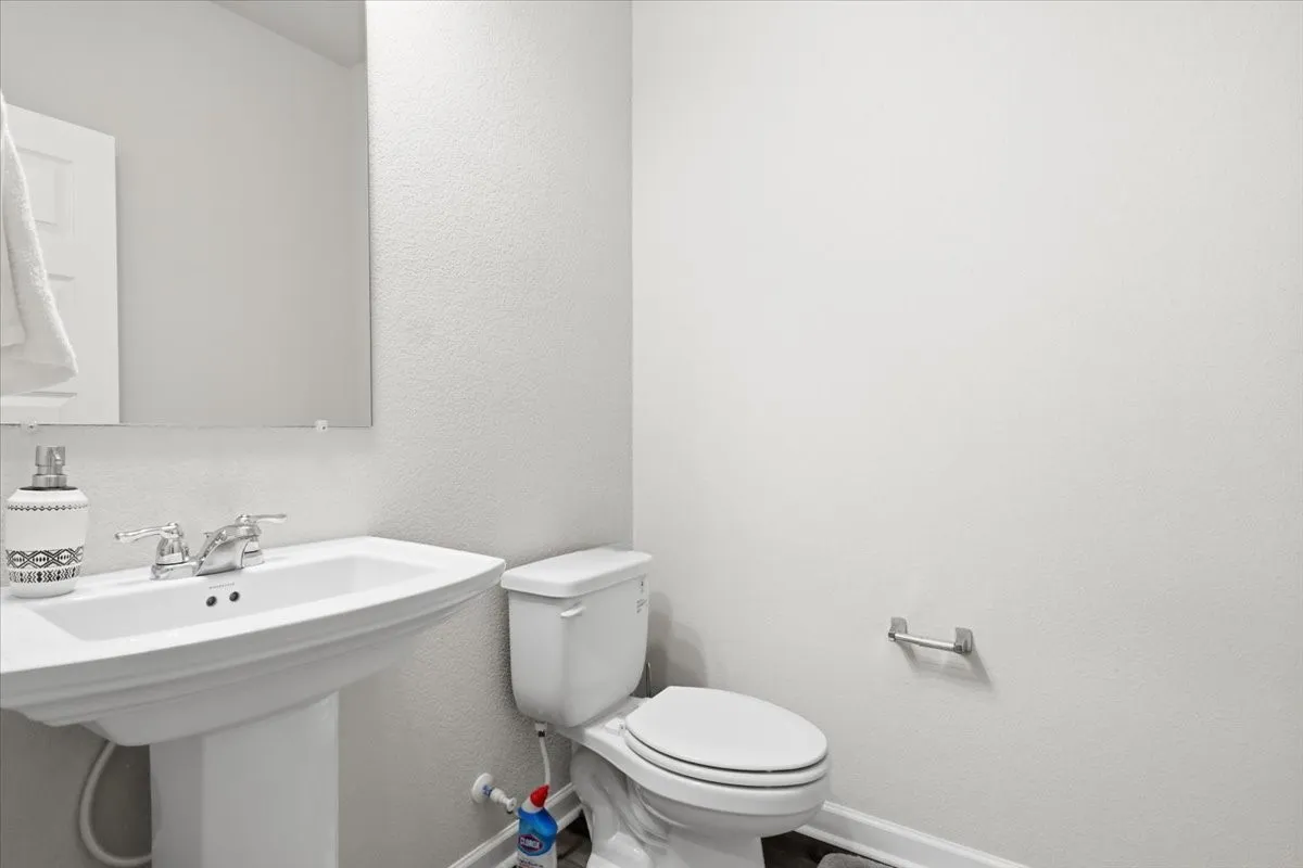 Pedestal sink with chrome fixtures and a wall-mounted mirror