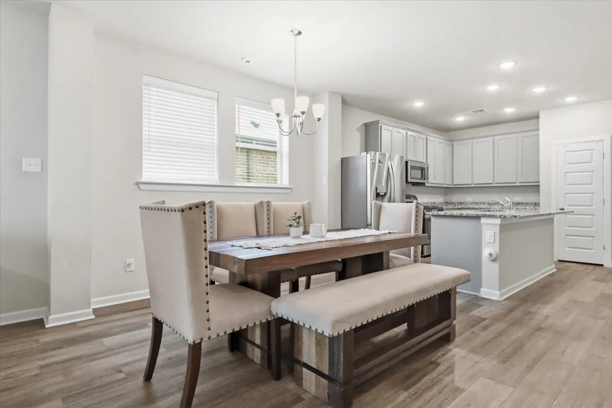 Open-concept living space with wood-finish flooring, recessed lighting, and a modern chandelier