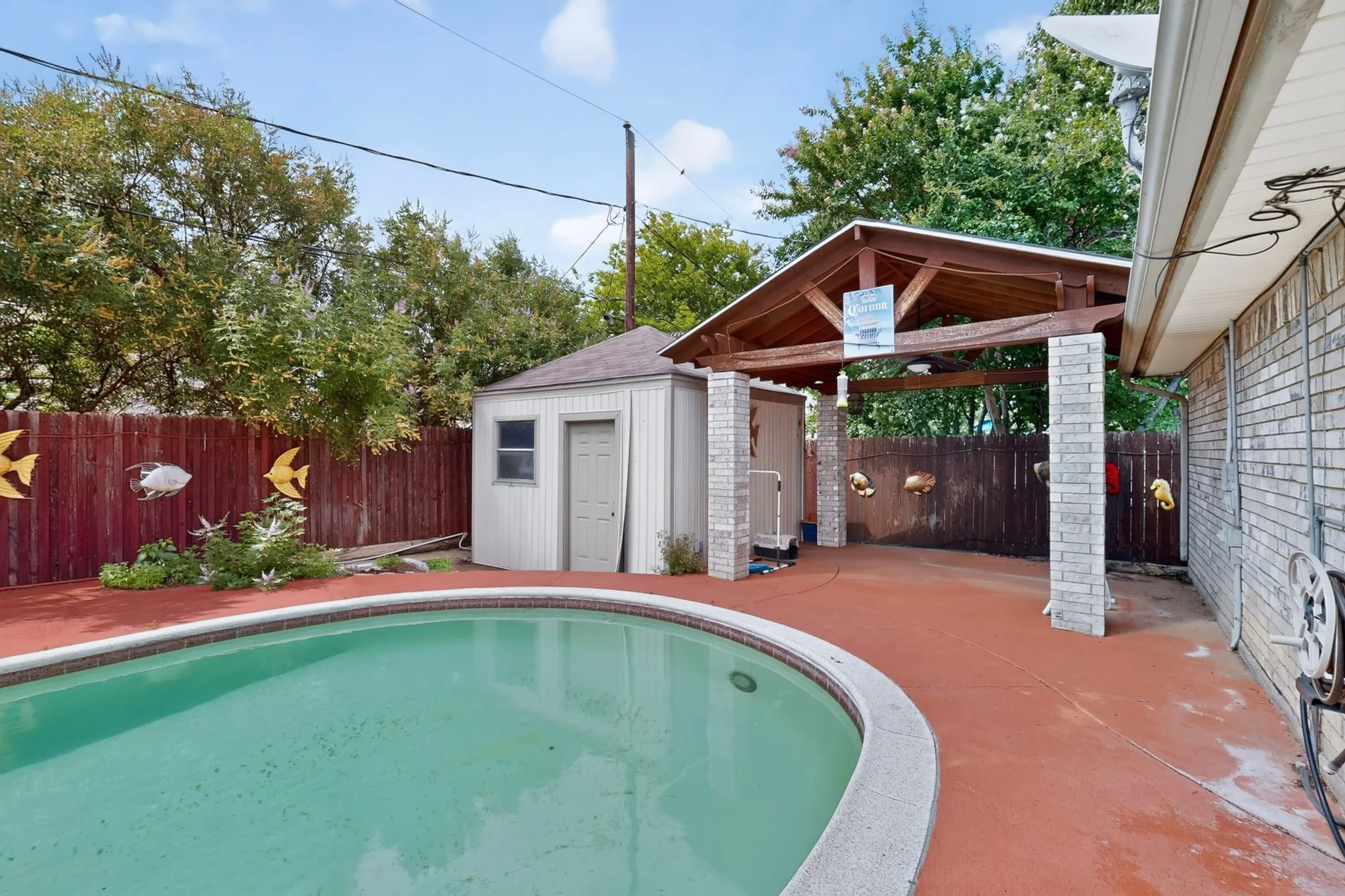 Outdoor swimming pool with a curved edge, surrounded by a red-toned concrete patio