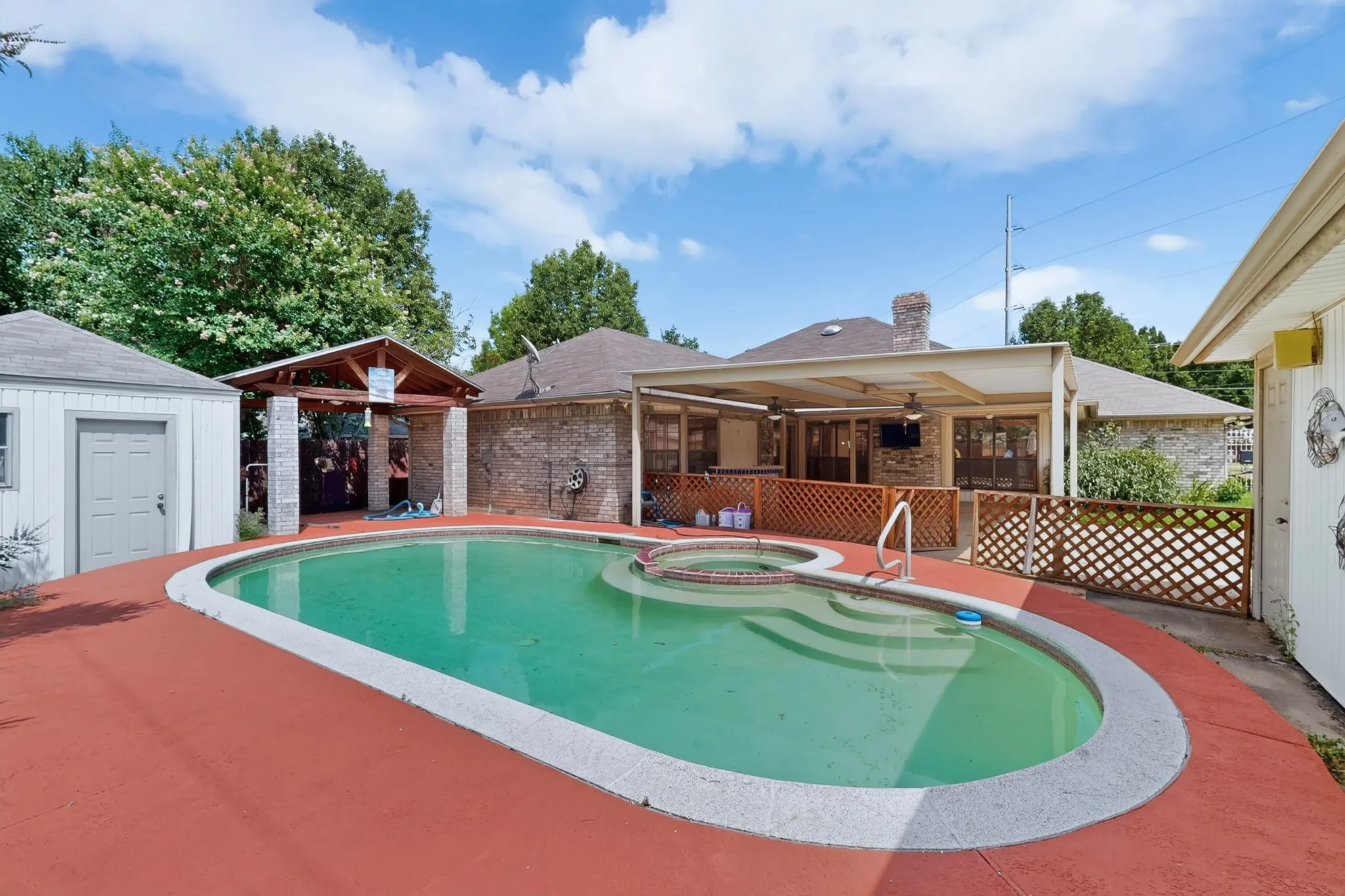 Outdoor swimming pool with integrated spa and red-painted concrete decking