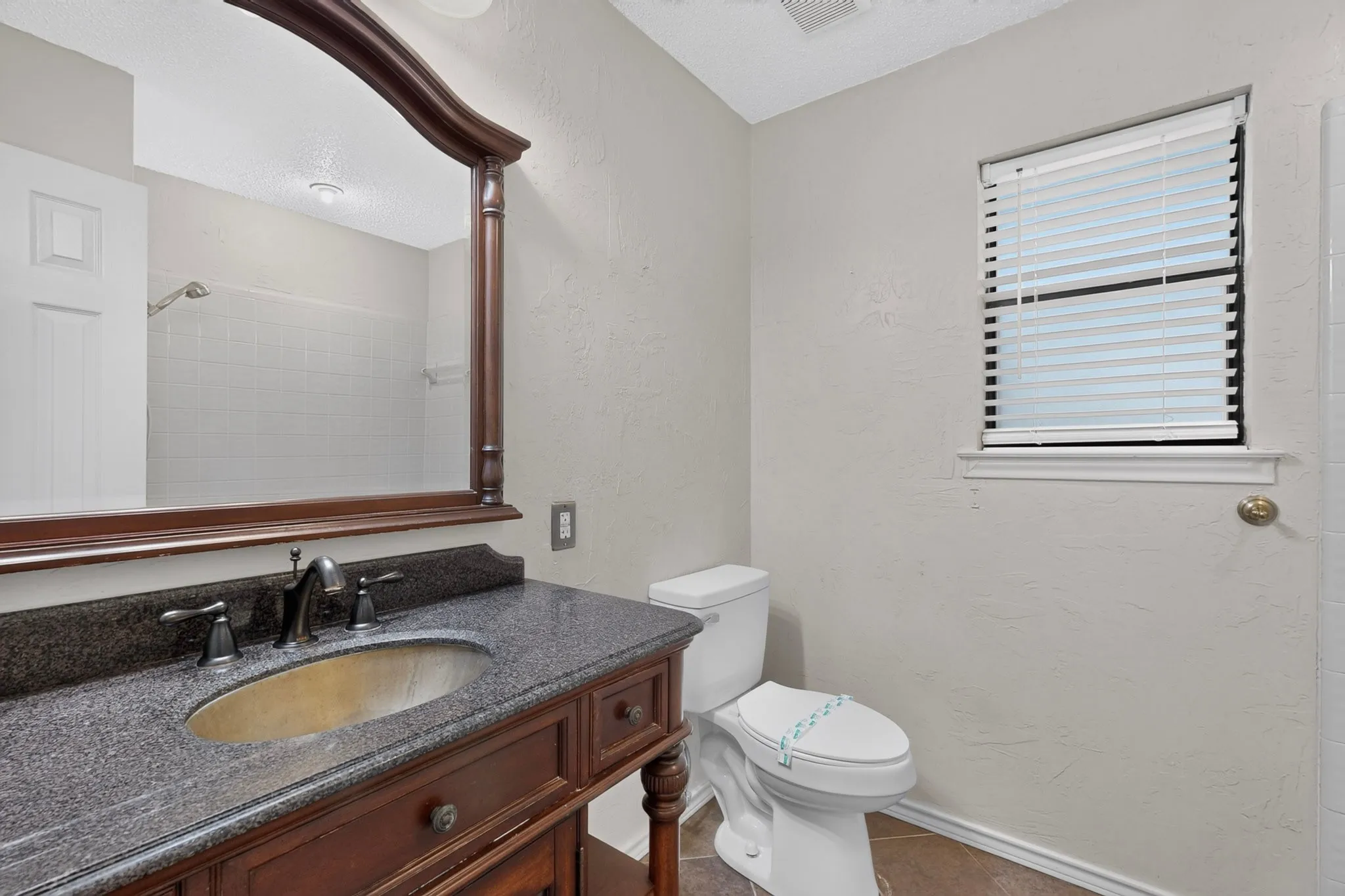Bathroom featuring a dark wood vanity with an undermount sink, stone countertop, and dark-finished faucet