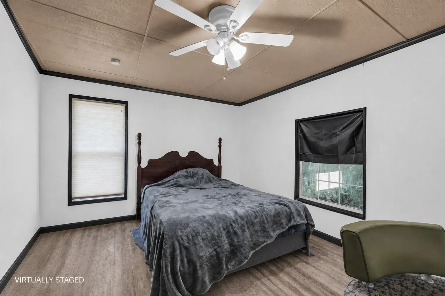 Room featuring wood-finish flooring, two windows with dark trim, and a ceiling fan with integrated lighting