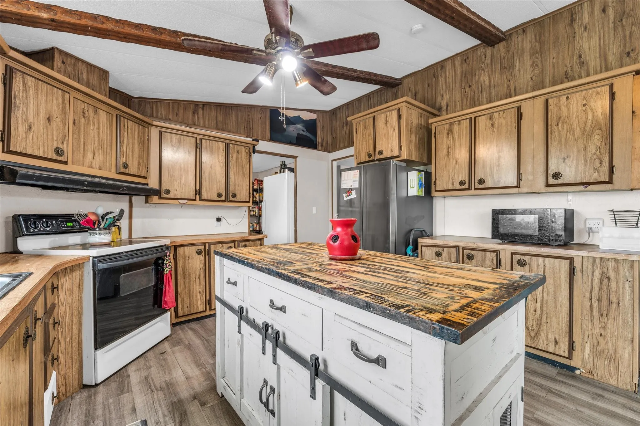 Kitchen featuring a rustic wood-finish island with barn door-style cabinetry, wood-look upper and lower cabinetry, wood-finish countertops, and wood-finish flooring