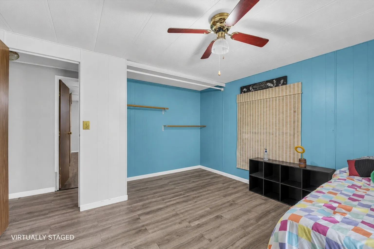 Room featuring wood-finish flooring, a ceiling fan with light fixture, and a window with blinds