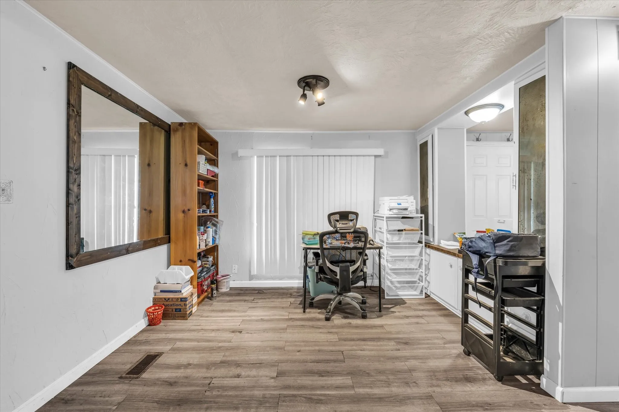 Wood-finish flooring throughout, featuring vertical blinds, track lighting, and built-in cabinetry