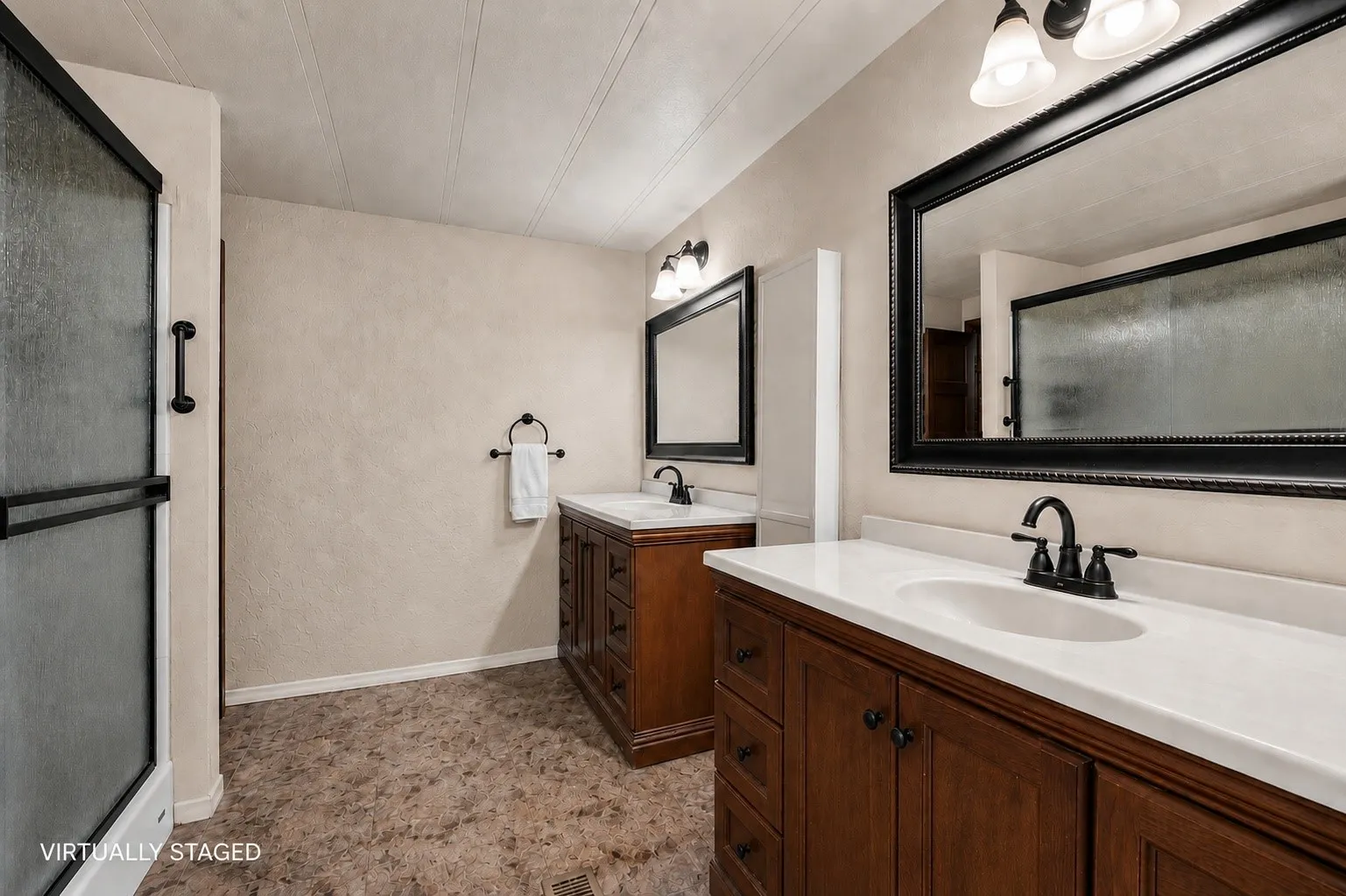 Bathroom featuring a dual vanity with wood cabinetry, white countertops, and black hardware